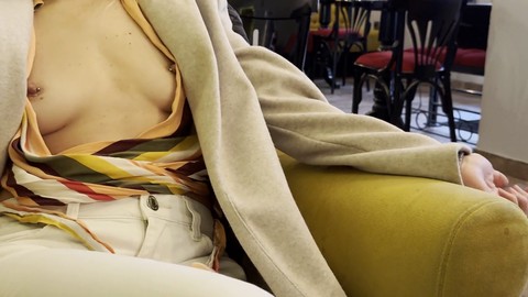 Esposa mostrando sus pechos perfectos y pezones perforados mientras toma café en un bar público